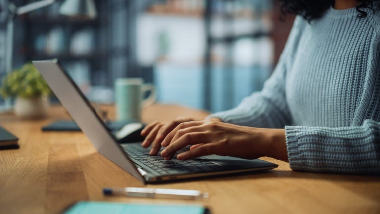 Woman typing on a laptop at a desk in a modern office.