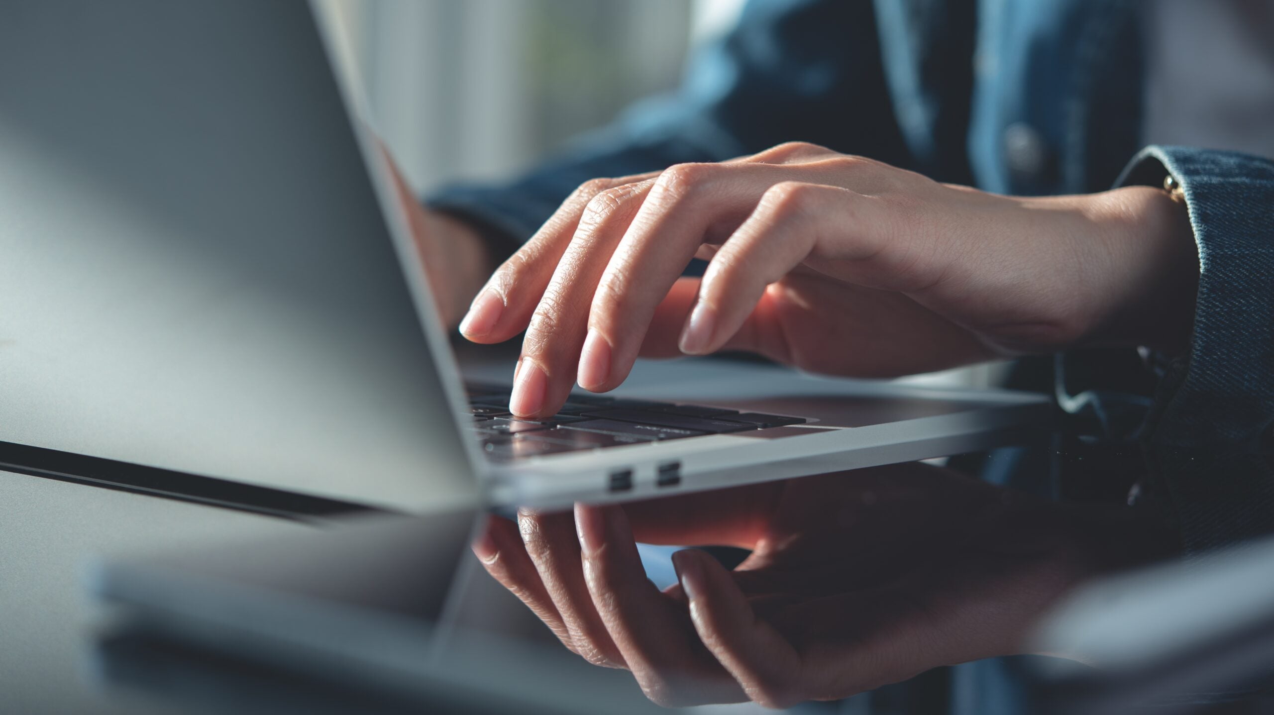 Closeup, business woman hands working and typing on laptop keyboard on glass table. Woman freelancer online working on laptop from home office, remotely work, distant job, social networking