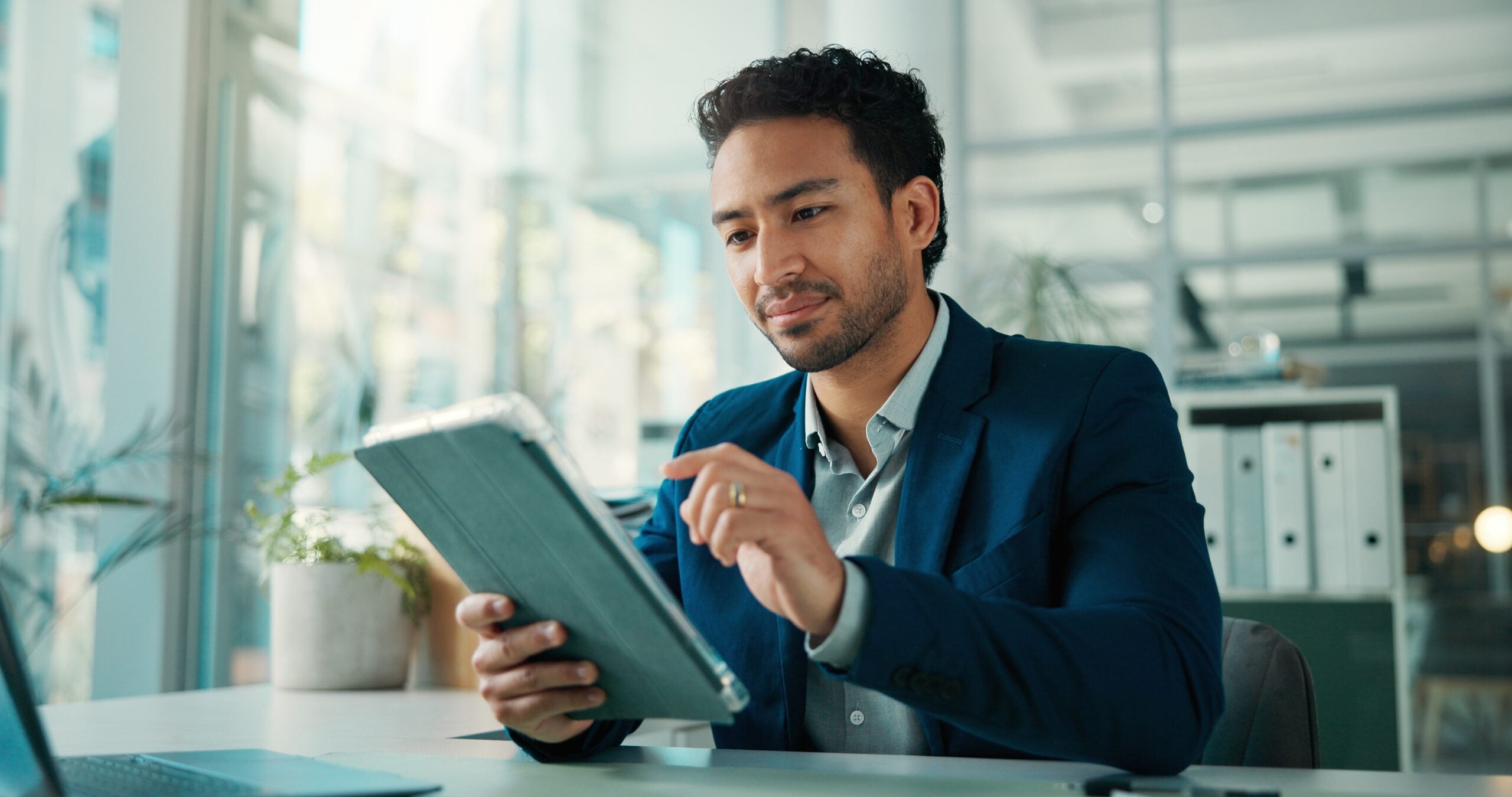 Office worker holding a tablet and using the touchscreen.
