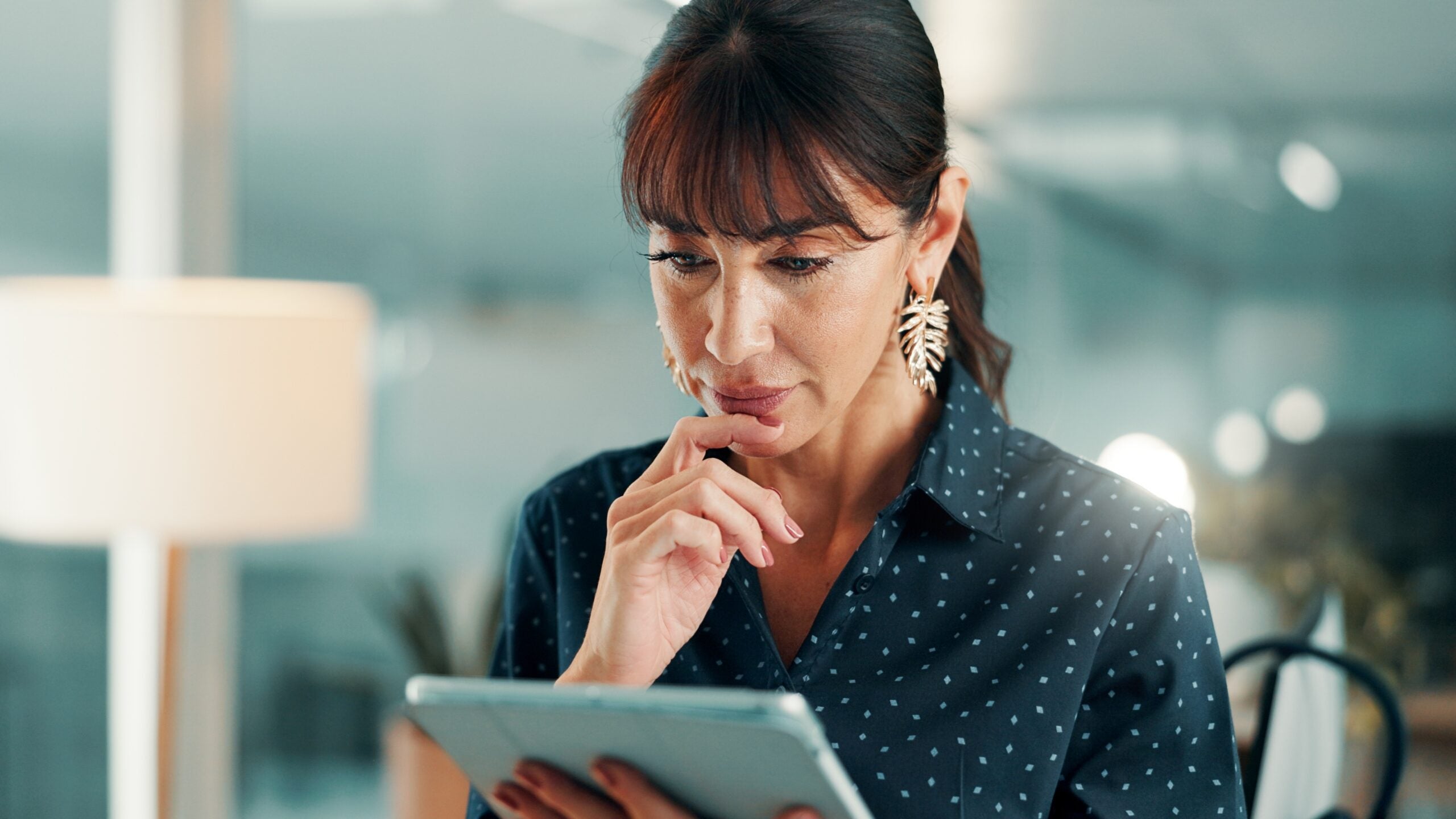 Woman looking thoughtfully at an iPad